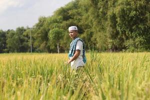 ung asiatisk muslim pojke i de ris fält foto