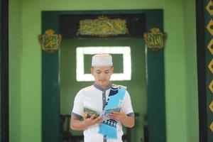ung asiatisk muslim bön- i de moské bärande en bön matta foto