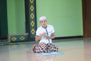 ung asiatisk muslim bön- i de moské foto