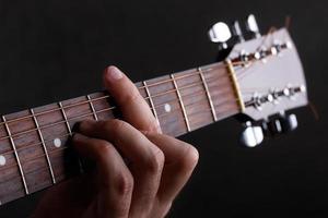 manlig hand som håller en barre på gitarr