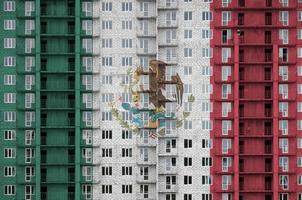 mexico flagga avbildad i måla färger på flera våningar bosatt byggnad under konstruktion. texturerad baner på tegel vägg bakgrund foto