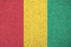 guinea flagga avbildad i ljus måla färger på gammal lättnad putsning vägg. texturerad baner på grov bakgrund foto