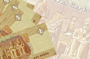 1 egyptisk pund räkningar lögner i stack på bakgrund av stor halvtransparent sedel. abstrakt företag bakgrund foto