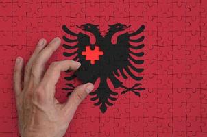 albania flagga är avbildad på en pussel, som de mannens hand slutförs till vika ihop foto