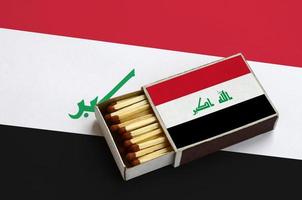 irak flagga är visad i ett öppen tändsticksask, som är fylld med tändstickor och lögner på en stor flagga foto