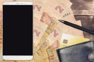 2 ukrainska hryvnias räkningar och smartphone med handväska och kreditera kort. e-betalningar eller e-handel begrepp. uppkopplad handla och företag med bärbar enheter foto