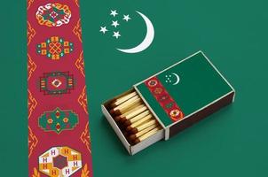 turkmenistan flagga är visad i ett öppen tändsticksask, som är fylld med tändstickor och lögner på en stor flagga foto