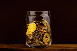 guld mynt i glas flaska på svart scen, pengar och guld sparande begrepp foto