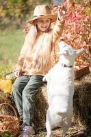 liten flicka spelar med hund i höst trädgård foto