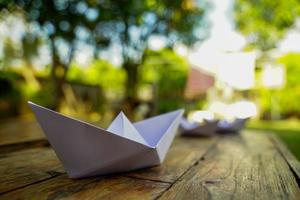 origami, vit papper båt isolerat på en trä- golv. papper båtar betyda gående. känsla av frihet ledarskap foto