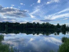 skön solnedgång på de sjö. moln och de silhuett av träd är reflekterad i de vatten. foto