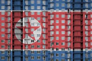 norr korea flagga avbildad i måla färger på flera våningar bosatt byggnad under konstruktion. texturerad baner på tegel vägg bakgrund foto