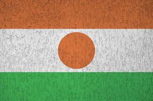 niger flagga avbildad i ljus måla färger på gammal lättnad putsning vägg. texturerad baner på grov bakgrund foto