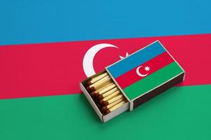 azerbaijan flagga är visad i ett öppen tändsticksask, som är fylld med tändstickor och lögner på en stor flagga foto