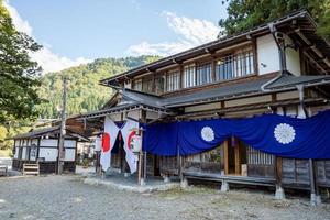 shirakawago, gifu, japan - oktober 2022 - shirakawa hachiman helgedom Port område på shirakawago by med tall träd och japansk flagga. foto