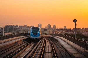 dubai, uae, 2022 - metro tåg på järnväg i dubai med solnedgång orange himmel bakgrund foto