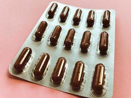 medicinsk farmaceutisk brun mediciner för de behandling av sjukdomar och de dödande av mikrober och virus tabletter och vitaminer blåsor blåsor från coronavirus covid-19 på en rosa bakgrund foto