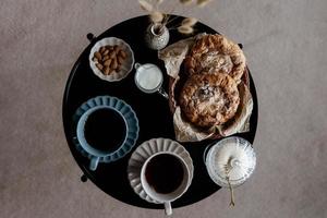 estetisk frukost. mjölk kaffe, mjölk te, socker, mandel, mandel kakor, kex, marsipaner och blossar. brittiskt frukost i en mysigt Hem. höst humör. foto