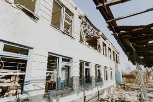 mariupol, ukraina - 19.11.2016 en förstörd skola i de frontlinjen by av shirokino. konsekvenser av de krig mellan ryssland och ukraina. soldat med ak-47. foto