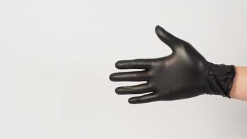 tömma hand är ha på sig svart latex handskar på vit bakgrund. foto