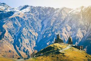 stepantsminda, georgien. känd populär gergeti trinity tsminda sameba kyrka i tidigt vinter- landskap. skön georgiansk bergen landskap foto