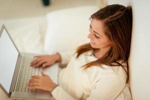 kvinna använder sig av bärbar dator i säng foto