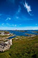 norskt sommarlandskap med hav, grön äng och djupblå himmel foto