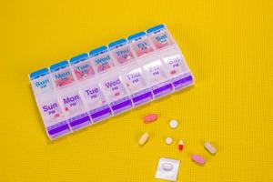 varje vecka piller låda behållare på mönstrad gul bakgrund foto