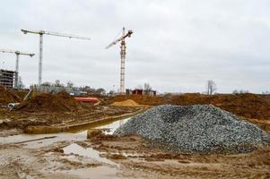 en stor modern konstruktion webbplats i de konstruktion av byggnader och hus med apparater och många stor hög torn och stationär industriell kraftfull kranar och byggnad material foto