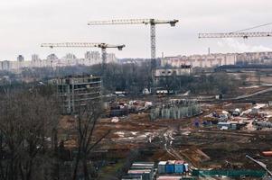 topp se av de konstruktion webbplats under de konstruktion av en ny hus egendom med lång hus, ny byggnader med de hjälp av stor industriell kranar och professionell Utrustning i en stor stad foto