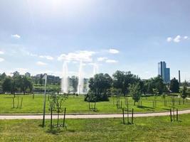 grön skön ung parkera i de Centrum av en stor stad med fontäner och plantor av små träd mot de bakgrund av byggnader foto