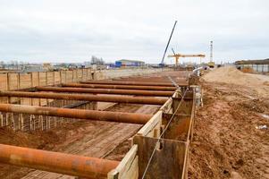 en stor enorm dike grop tunnel med förstärkande strukturer från tjock järn rör av balkar och strukturer på de konstruktion webbplats av de underjordisk metro station linje foto