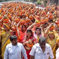 New Delhi, Indien 3 april 2022 - kvinnor med kalash på huvudet under jagannath-templet mangal kalash yatra, indiska hinduistiska hängivna bär jordkrukor som innehåller heligt vatten med en kokosnöt på toppen foto