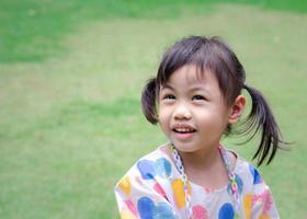 porträtt av Lycklig charmig 4 år gammal söt bebis asiatisk flicka, liten preschooler barn leende ser upp med kopia Plats. foto