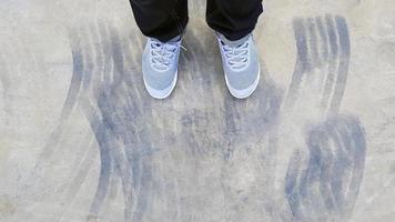 topp se av ben bär blå jeans och grå eller grå gymnastikskor eller mode skor på golv med bil hjul eller broms mark på väg eller gata med kopia Plats. platt lägga av del kropp. abstrakt bakgrund foto