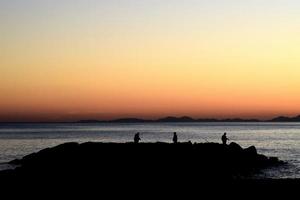 silhuett av tre fiskare på ön under den gyllene timmen foto