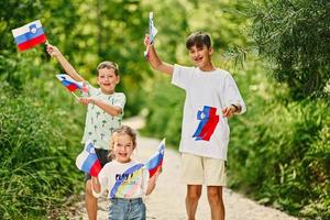 tre barn håll slovenska flaggor i triglav nationell parkera, slovenien. foto