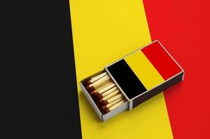 belgien flagga är visad i ett öppen tändsticksask, som är fylld med tändstickor och lögner på en stor flagga foto