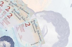 2 venezuelanska bolivar räkningar lögner i stack på bakgrund av stor halvtransparent sedel. abstrakt företag bakgrund foto