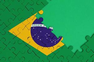 Brasilien flagga är avbildad på en avslutad kontursåg pussel med fri grön kopia Plats på de rätt sida foto