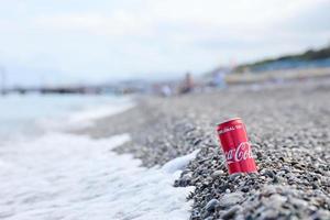 antalya, Kalkon - Maj 18, 2021 original- coca cola röd tenn kan lögner på små runda sten stenar stänga till hav Strand. Coca Cola på turkiska strand foto