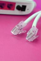 internet router och internet kabel- pluggar lögn på en ljus rosa bakgrund. objekt nödvändig för internet foto