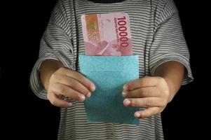 hand av ung unge innehav indonesiska pengar. rupiah, idr pengar. foto