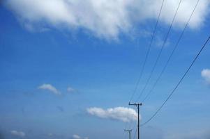 elektrisk Pol kraft rader utgående elektrisk trådar motstånd på moln blå himmel. foto