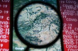 Spanien Land på Google Kartor under förstorande glas med röd covid-19 text bakgrund. selektiv fokus. foto