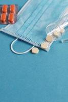 medicinsk mask, spruta, tabletter och ampuller med medicin på de blå bakgrund. coronavirus, influensa, sjukdom begrepp. foto