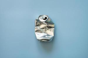 skrynkliga aluminium tömma soda eller öl burk, på en blå bakgrund. topp se. foto