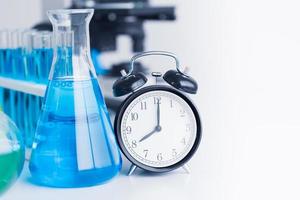 tid klocka med kemisk glas för medicinsk vetenskap forskning i laboratorium foto