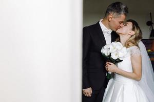 brudgummen kysser bruden i ett hotellrum foto