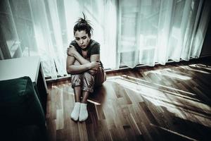 kvinna känsla depression medan Sammanträde nära de fönster på Hem foto